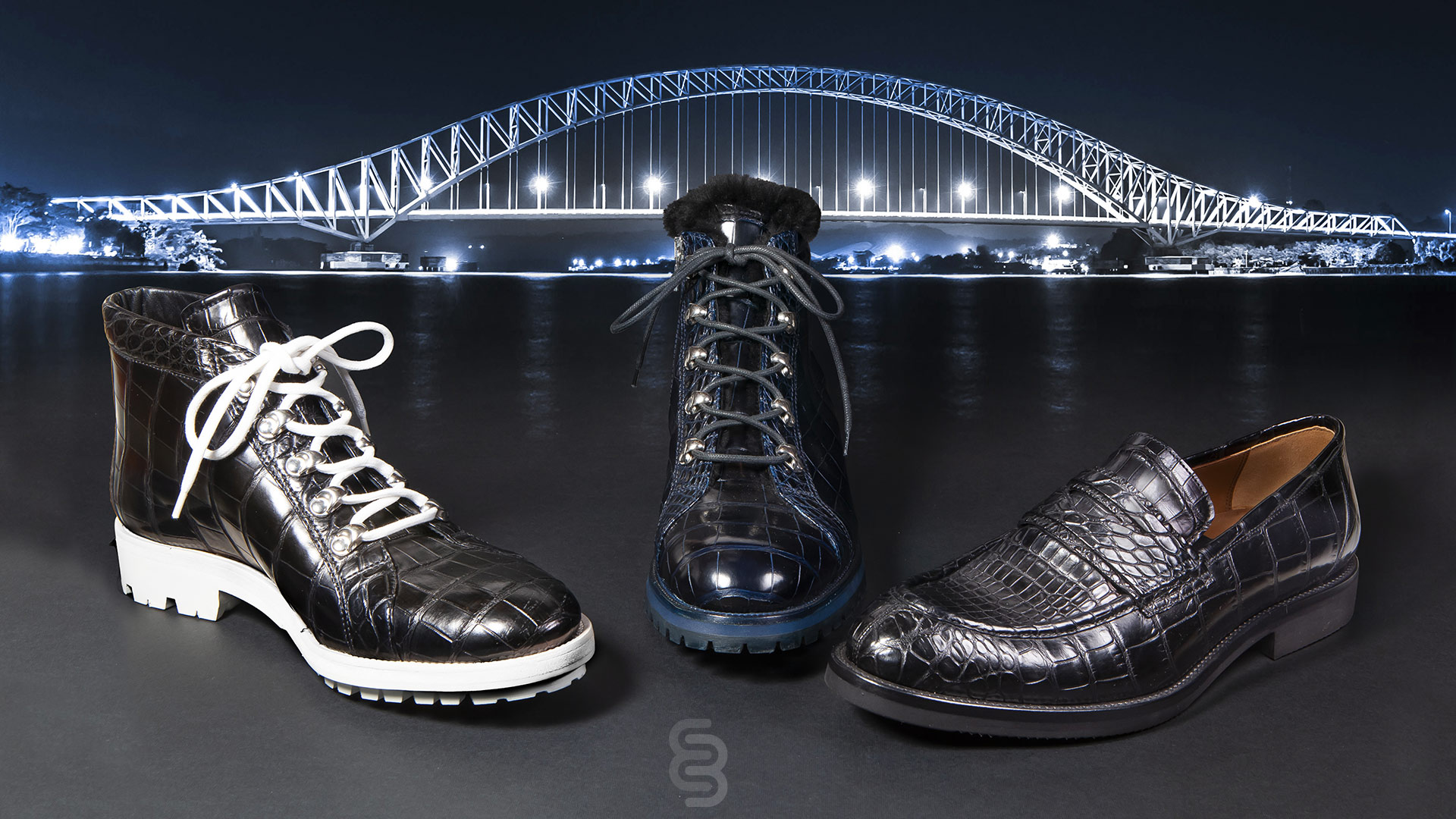 tre scarpe in primo piano, sullo sfondo ponte illuminato